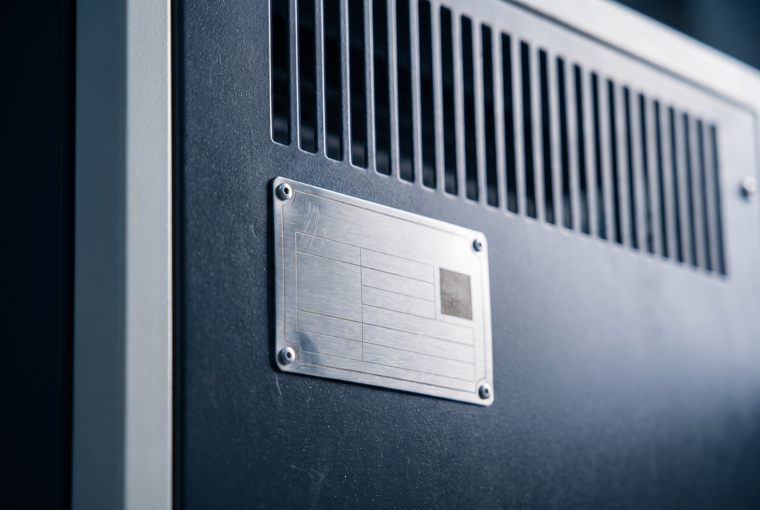 A metal nameplate fixed to the body of a unit, carrying serial number and service code fields